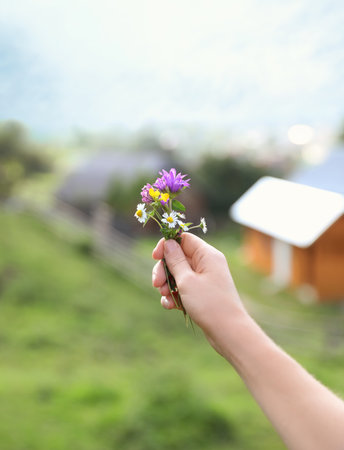 Woman holding bouquet of beautiful meadow flowers against blurred backgroundの写真素材