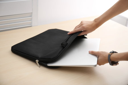 Woman laptop into case at table, putting closeupの写真素材