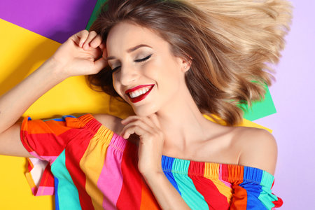 Beautiful young woman with healthy long blonde hair on color background, top viewの写真素材