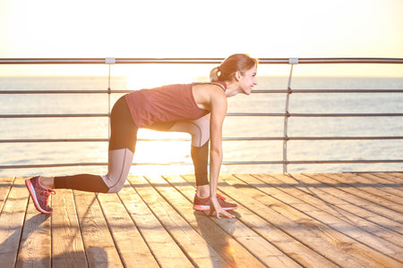 Fitness woman in position ready to run on pier in the morning