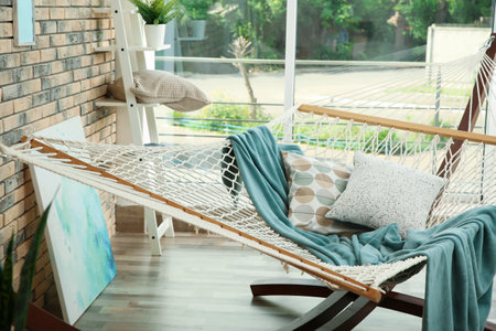 Comfortable hammock with plaid and pillows in living roomの写真素材
