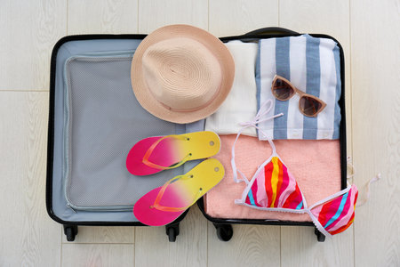 Open suitcase with female clothing and accessories on wooden backgroundの写真素材