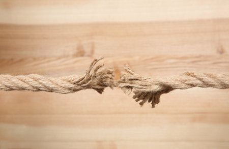 Frayed rope at breaking point on wooden background