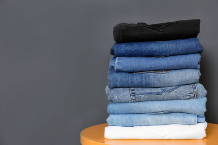 Stack of different jeans on table against gray background. Space for textの写真素材