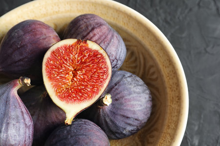 Bowl with fresh ripe figs on dark background, top viewの写真素材