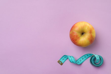 Fresh apple and measuring tape on color background, top view. healthy dietの写真素材