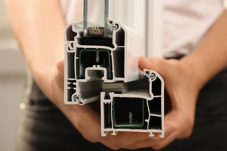 Woman holding sample of modern window profile, closeup