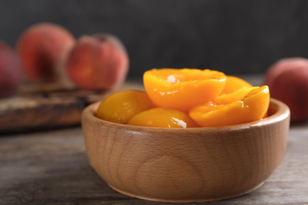 Bowl with canned peach halves on wooden table. Space for textの写真素材