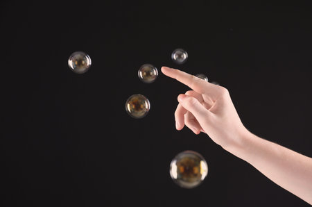 Woman popping soap bubbles on dark background, closeupの写真素材