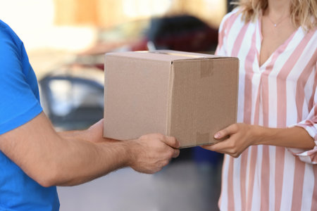 Woman parcel receiving from deliveryman on blurred background, closeup. Space for textの写真素材