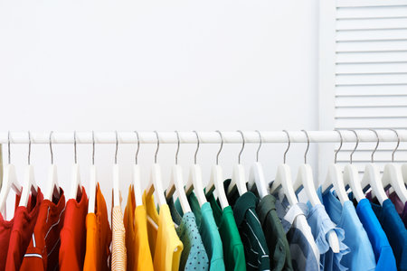 Rack with bright clothes in the room. Rainbow colorsの写真素材