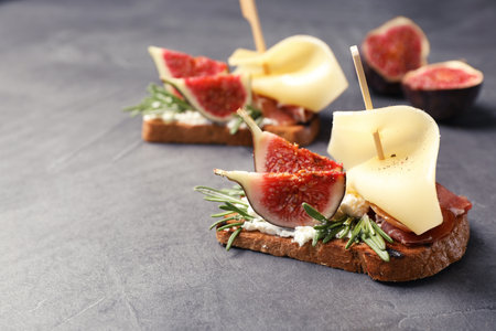 Sandwich with ripe fig, prosciutto and cheese on gray background, closeupの写真素材