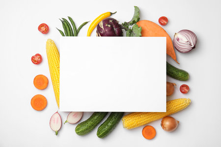 Flat lay composition with fresh vegetables and blank card for text on white backgroundの写真素材