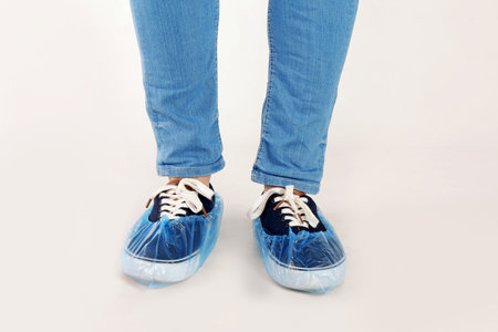 Man with blue shoe covers worn over sneakers on white background, closeupの写真素材