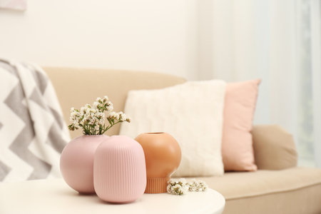 Beautiful ceramic vases and flowers on table in living roomの写真素材