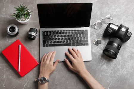 Female photographer using laptop at table, top viewの写真素材