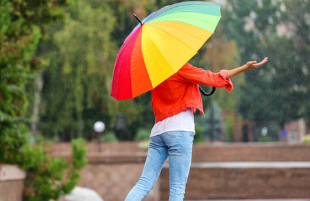 Young woman with bright umbrella under rain outdoorsの写真素材