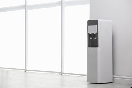 Modern water cooler near white wall indoors. Space for textの写真素材