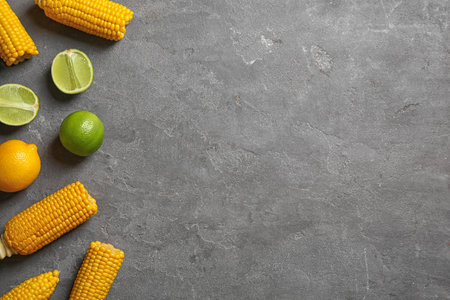 Flat lay composition with corn cobs and citrus fruits on gray background. Space for textの写真素材