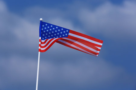 Small American flag against cloudy blue skyの写真素材