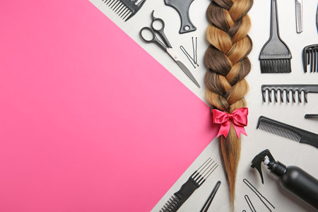 Flat lay composition with braid, hairdresser's tools and space for text on color backgroundの写真素材
