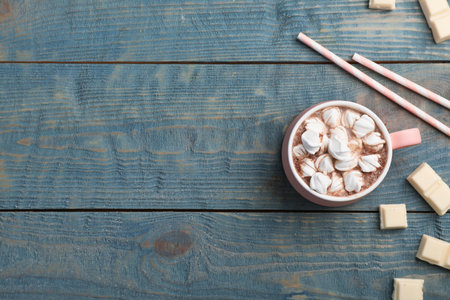 Cup of chocolate milk with marshmallows on wooden background, flat lay. Space for textの写真素材