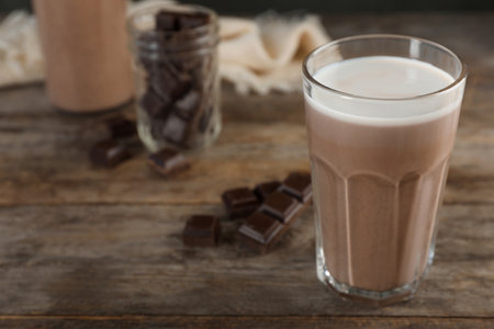 Glass of chocolate milk on wooden table, closeup. Space for textの写真素材