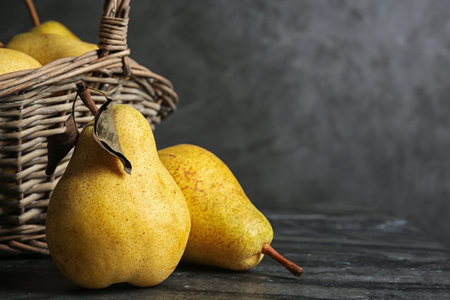 Basket of fresh ripe pears on table against gray background with space for textの写真素材