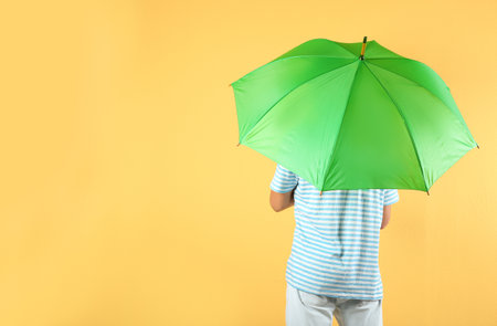 Man with green umbrella on color backgroundの写真素材