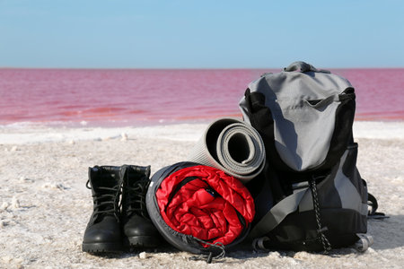 Set of camping equipment with sleeping bag on coast of pink lakeの写真素材