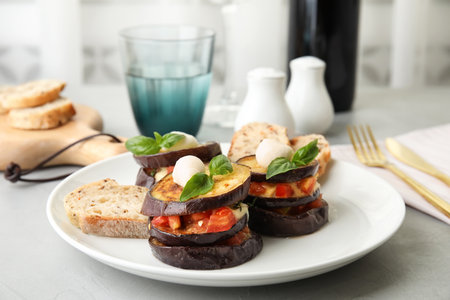 Baked eggplant with tomatoes, cheese and basil served on tableの写真素材