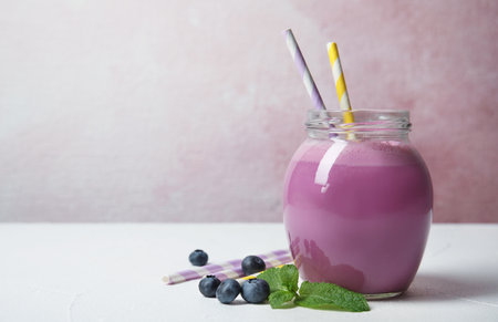 Jar of tasty milk shake and blueberries on table. Space for textの写真素材