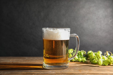 Composition with tasty beer and fresh green hops on wooden tableの写真素材