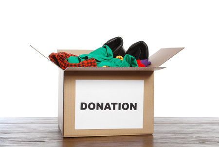 Donation box with clothes and shoes on table against white backgroundの写真素材