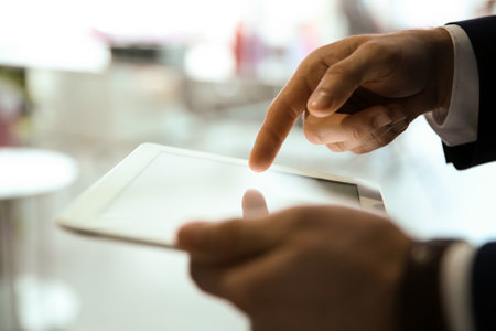 Businessman using digital tablet at workplace, closeup of hand. Mockup for design