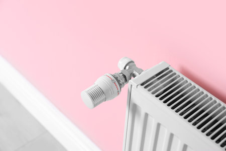 Heating radiator with thermostat near color wallの写真素材