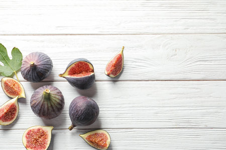 Flat lay composition with whole and cut purple figs and space for text on wooden backgroundの写真素材