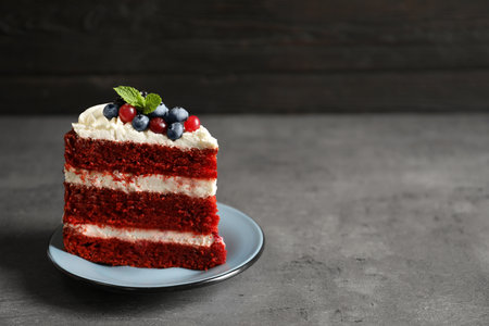 Plate with piece of delicious homemade red velvet cake and space for text on blurred background