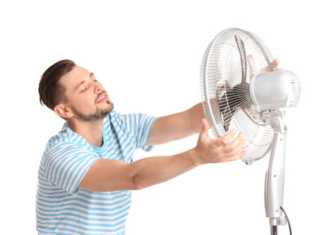 Man refreshing from heat in front of fan on white backgroundの写真素材