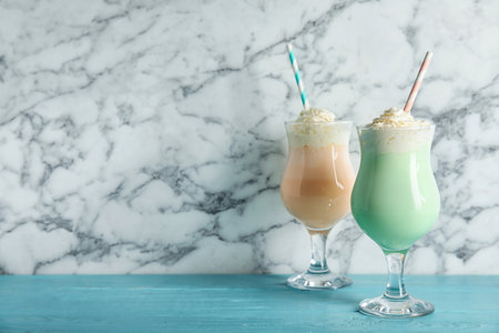Glasses with delicious milk shakes on table against marble background. Space for textの写真素材