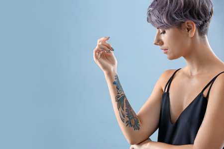 Young woman with tattoo on color background. Space for textの写真素材