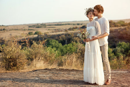 Happy newlyweds with beautiful field bouquet outdoorsの写真素材