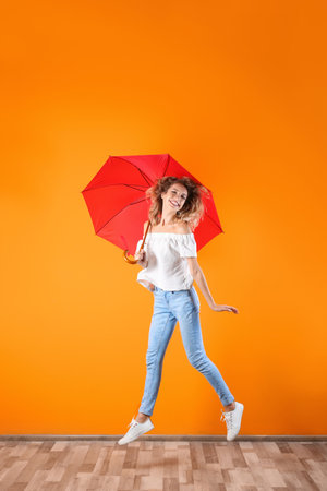 Woman with red umbrella near color wallの写真素材