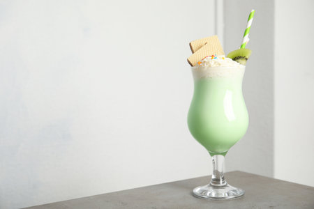 Glass with delicious milk shake on table against light background. Space for textの写真素材