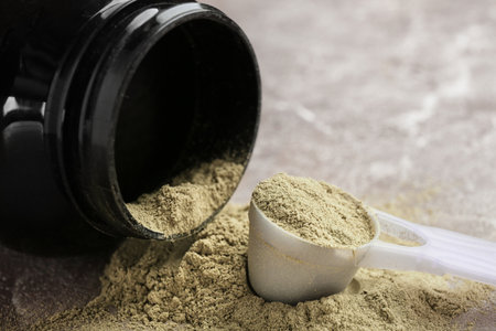 Jar and measuring spoon with hemp protein powder on tableの写真素材