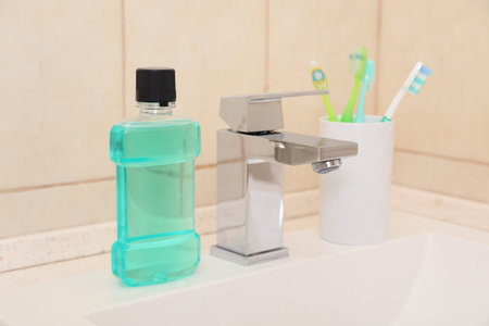 Mouthwash and holder with toothbrushes on sink in bathroom. Teeth and oral careの写真素材