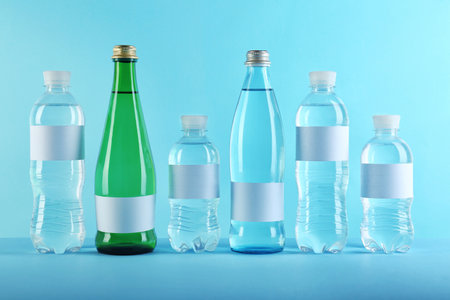 Different bottles of pure water with blank tags on color backgroundの写真素材