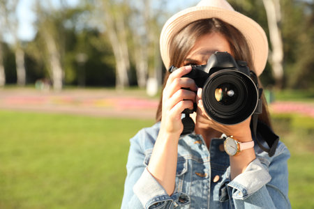Young female photographer taking photo with professional camera on street. Space for textの写真素材