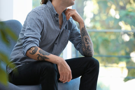 Young man with stylish tattoos at homeの写真素材