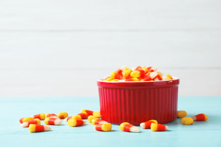 Bowl with delicious candies on table against wooden backgroundの写真素材